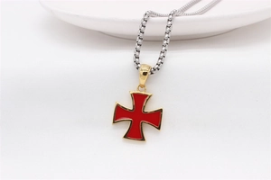 Close-up of a retro red enamel cross pendant with golden edges on a silver chain