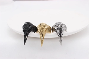 Detailed macro view of three vintage Viking bird skull rings in black, gold, and silver finishes