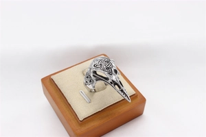 Detailed macro view of silver raven skull ring featuring intricate Celtic knot engravings