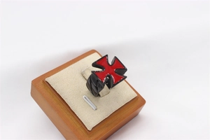 Macro detail of men's gothic ring with red Malta cross design on a black steel band