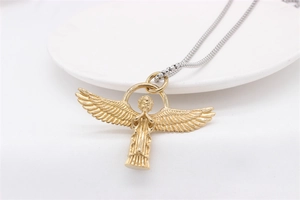 Detail of a vintage golden Cupid angel pendant with prayer hands on a white plate