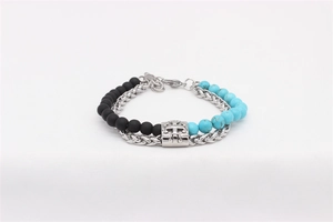 Detail view of double-layer beaded bracelet with turquoise beads and a metal cross charm