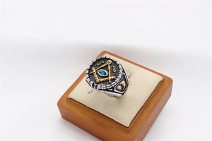 Macro shot of Freemason steel ring with golden compass symbol and blue gem inlay