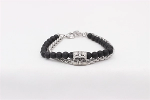 Detail of double-layer bracelet with black lava stones and silver wheat chain with cross charm