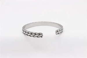 Macro shot of retro silver steel cuff bracelet featuring detailed industrial scale textures