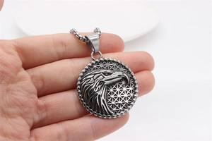 Detailed shot of retro eagle relief pendant necklace held by hand on white background