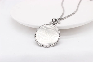 Detailed close-up of a silver eagle pendant necklace on white ceramic surface