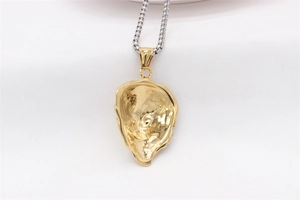 Macro detail of gold oyster shell pendant back with textured finish and silver box chain