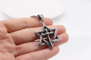 Macro detail of vintage hexagram cross pendant with textured steel engraving on box chain