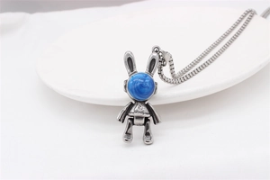 Détail macro du pendentif lapin rétro avec pierre bleue et finition acier sur plateau blanc