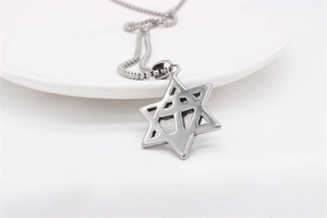 Macro detail of silver hexagram pendant on bead chain against white background