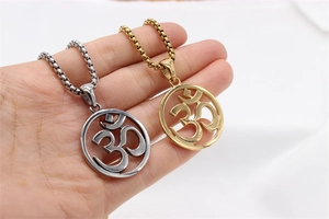 Détail de pendentifs symbole Om en argent et or sur chaînes box sur tissu blanc