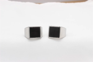 Macro view of two men's stainless steel signet rings with square black stone inlay