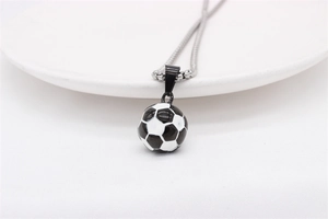 Gros plan d'un collier pendentif football en émail noir et blanc sur une assiette blanche