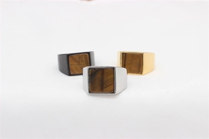 Detailed view of three-piece men's signet rings in gold, silver, and black with tiger eye stones