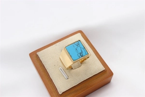 Macro view of square blue turquoise gemstone on a minimalist golden titanium steel ring