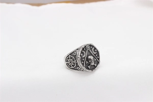 Macro shot of vintage titanium steel ring with skull, compass and mystical geometric patterns
