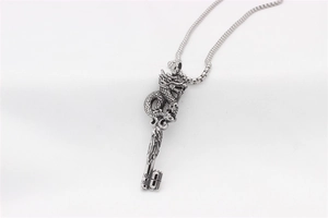 Macro shot of silver dragon key pendant with detailed scales and engraved textures
