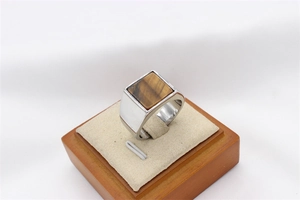 Macro detail of men's square tiger eye stone ring set in a thick silver steel band