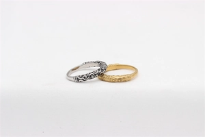 Close-up of vintage titanium steel rings with intricate gold and silver cloud carvings