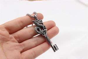 Detail of vintage silver dragon key pendant with intricate engravings and box chain necklace