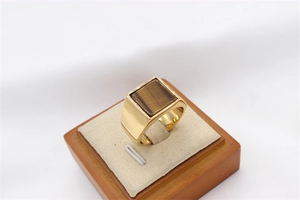 Macro shot of men's gold plated signet ring with a square tiger eye stone inlay