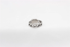 Macro view of silver Cuban link chain ring with rectangular plaque on white fabric