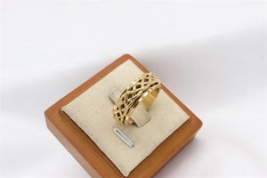 Macro detail of golden stainless steel spinner ring featuring Celtic weave texture