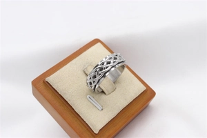 Close-up of rotatable stainless steel spinner ring with Celtic knot pattern on wood stand