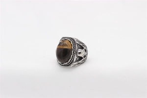 Detailed macro shot of vintage tiger eye gemstone and eagle wing carvings on steel ring
