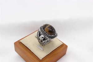 Detailed macro shot of vintage eagle relief and tiger eye gemstone on a steel ring