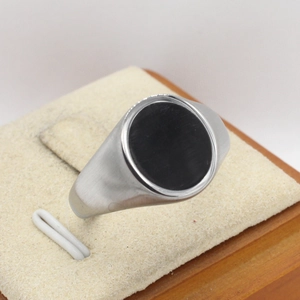 Men's silver titanium ring with oval black stone and brushed metal finish on display