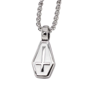 Macro detail of gothic coffin pendant with white enamel and silver inverted cross on a chain