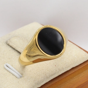 Men's gold signet ring with a large oval black stone set on a minimal steel band