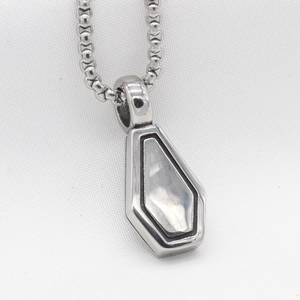 Macro view of gothic silver cross necklace with pearl-like inlay on coffin pendant