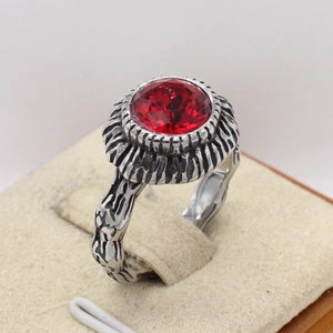 Close-up of vintage steel ring with textured bark finish and red faceted gemstone