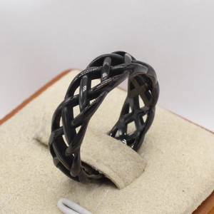 Close-up of black braided stainless steel ring with hollow weave design on a display stand