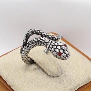 Macro shot of vintage snake ring with scale texture and red gemstone eyes on display