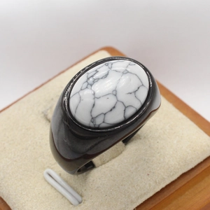 Polished stainless steel ring with an oval white turquoise stone on a wooden jewelry display