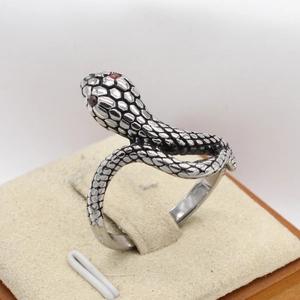Close-up of vintage snake ring with textured scales and red gemstone eyes