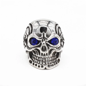 Retro punk skull ring in silver steel featuring deep blue gemstone eyes on white background