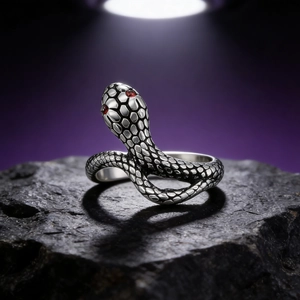 Retro snake ring in vintage silver steel with red gem eyes on dark rock display