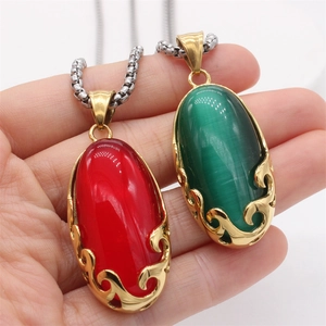 Detail of vintage red and green gemstone pendants with golden filigree edge on silver chain