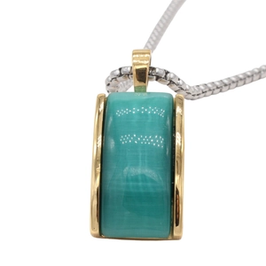 Detailed macro view of rectangular turquoise gemstone pendant with golden metallic border