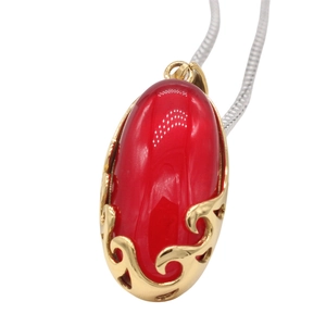 Detailed macro view of vintage red oval gemstone pendant with gold filigree and silver chain