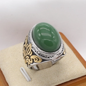 Makro-Detail des Herren-Retro-Rings mit grünem Edelstein und goldener Lilien-Verzierung