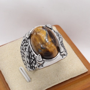 Détail de la bague griffe de dragon rétro avec pierre oeil de tigre et texture d'écailles