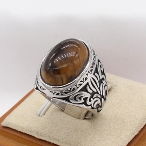 Makro-Detail von Vintage-Herrenring aus Stahl mit Tigerauge und floralem Reliefmuster