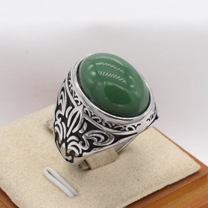 Makroaufnahme von Vintage-Titanstahlring mit grünem Edelstein und Blumen-Gravurdetails