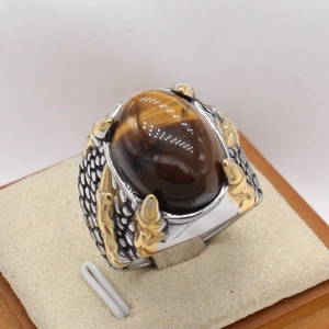 Détail d'une bague oeil de tigre avec texture écaille de dragon et griffes dorées